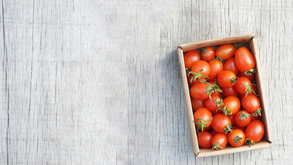 Red ripe tomatoes in box on wood background