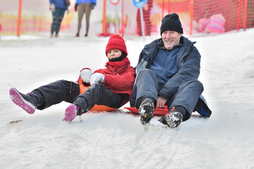 Family girl  man woman sledding on the snow from the winter hill