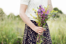Mid Section Of Woman Holding Bunch Of Flowers In Meadow