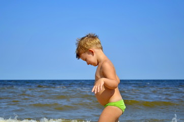 Cute little boy running through the water at the beach