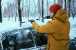young man clean car after snow storm