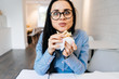 © mnelen.com - funny young girl student in a blue shirt and glasses eating a sandwich in a cafe