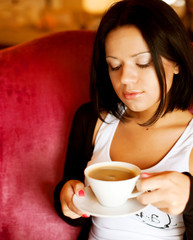 Wall Mural - young woman sitting in a cafe drinking coffee