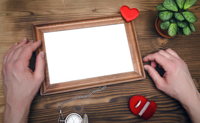 Wall Mural - Photo frame with copy space in male hands and wedding ring in a present box. Declaration of love. Offer to get married. Miss of girl friend.