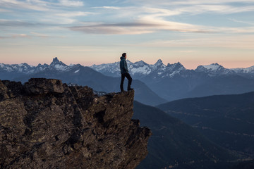 Adventurous man on top of the mountain during a vibrant sunset. Taken on Cheam Peak, near Chilliwack, East of Vancouver, British Columbia, Canada.