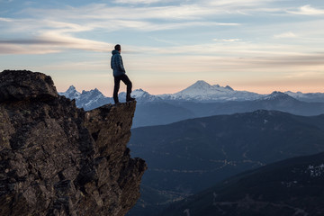 adventurous man on top of the mountain during a vibrant sunset. taken on cheam peak, near chilliwack
