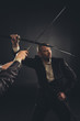 © LIGHTFIELD STUDIOS - strong mature businessman fighting with katana sword isolated on black