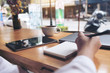 © Farknot Architect - Closeup image of woman's hand writing on a blank notebook with laptop , tablet and coffee cup on wooden table background