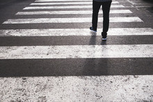 Low Section Of A Pedestrian Crossing The Road From The Marked Crosswalk