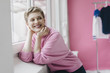 © Westend61 - Happy woman wearing pink sweatshirt at the window