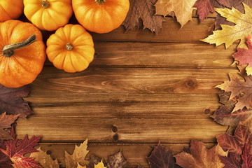 Wall Mural - Pumpkins with fall leaves over wooden background. Top view.