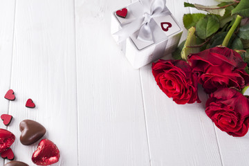 Wall Mural - Valentines concept with bouquet of roses and wrapped gift on wooden table