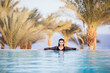 © F8  \ Suport Ukraine - girl in the infinity pool on the rooftop hotel relax in the water on sea and palms background