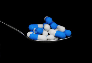 Metal spoon and medicine pills and tablets, on black background, medicine and addiction concept