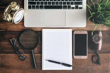 Notebook, laptop, magnifying glass, camera, phone and clock on a wooden table. blogger and jurnalist concept