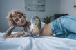 beautiful inked girl with pink hair lying on bed and looking at camera