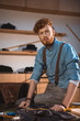 © LIGHTFIELD STUDIOS - handsome young fashion designer looking at camera while sitting on table at workplace