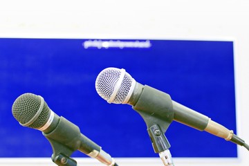 The two black and silver microphones on the microphone stand have a blue background.