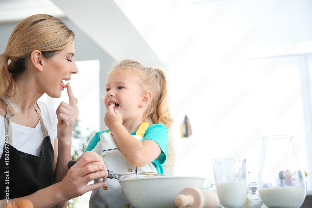 Mother and daughter preparing dough indoors
