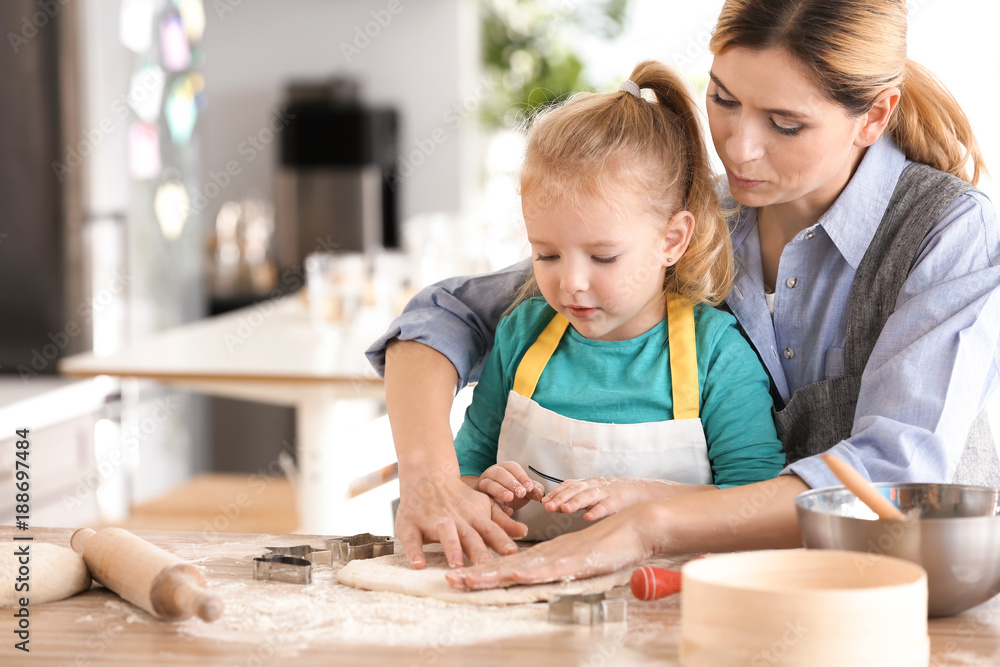 Mother and daughter with dough at table indoors