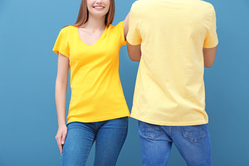 Sticker - Young woman and man in yellow t-shirts on color background. Mockup for design