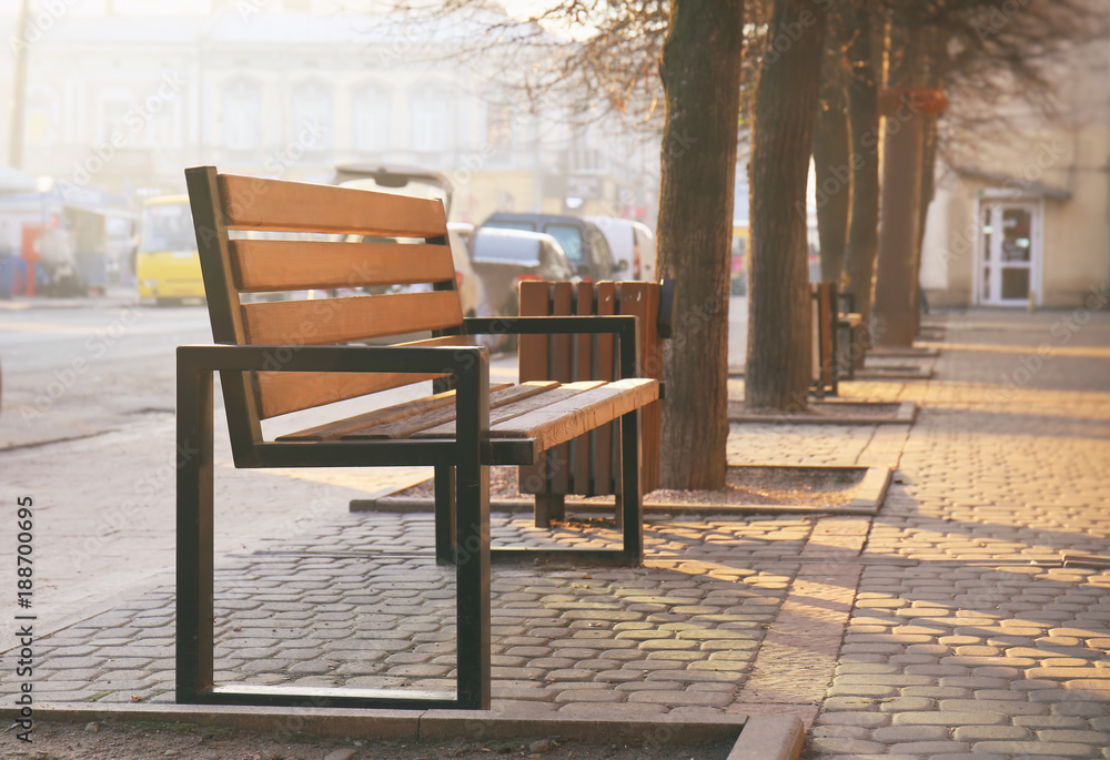 Wooden bench on sidewalk in city