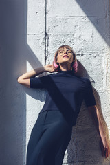 Wall Mural - stylish girl in black clothes leaning on wall and looking up