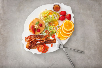 Wall Mural - Delicious pancakes with fried bacon, vegetables and fruits on plate