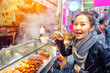 Asian young womanl eating Grilled octopus on a street in Hong Kong