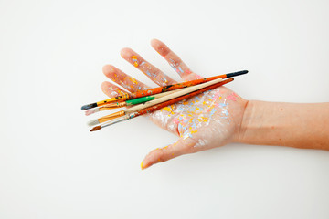 hand of artist holding set of paint brushes on white background with space for text. Isolated image