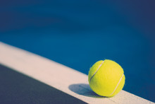 One New Tennis Ball On White Diagonal Line In Blue Hard Court With Light From Right, Shadow And Copy Space On Left, Vintage Tone