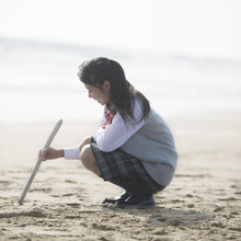 砂浜に絵を描く女子校生