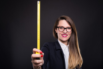 Young happy girl showing a yellow tape measure