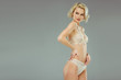 blonde model posing in white lace lingerie, isolated on grey