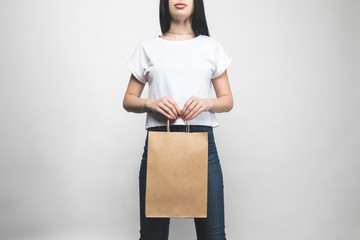 Wall Mural - young woman in blank t-shirt on white with shopping bag