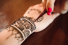 Master Mehndi Draws Henna On A Female Hand.