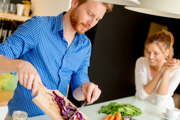 Wall Mural - Young couple preparing healthy meal in the kitchen