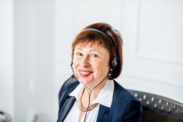 Close-up portrait of an elegant senior businesswoman working online with headset at the office