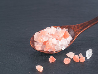 Wall Mural - Himalayan pink salt in spoon on black stone background. Copy space