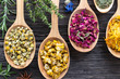 Herbs on spoons on a wooden background, top view