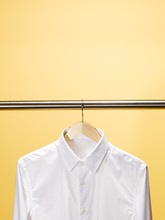 White Shirt Hanging Hanger Against Yellow Background