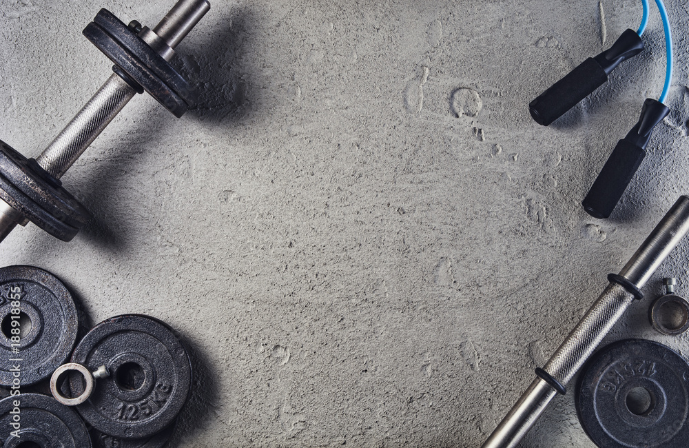 Fitness or bodybuilding concept background. Product photograph of old iron dumbbells on grey, conrete floor in the gym. Photograph taken from above, top view with lots of copy space - obrazy, fototapety, plakaty 