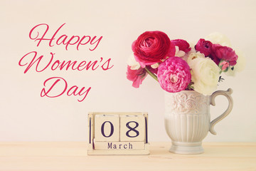 International women day concept with beautiful flowers in the vase and date on wooden table.