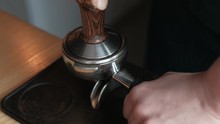 Barista Compresses Coffee Grounds With Tamper. Making Coffee Process. Barista's Hands With Tamper.