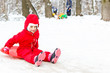 © Angelov - Pretty smiling little girl in her ski suit sliding down a small snow covered hill with her sledge