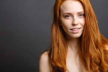 Wall Mural - Beautiful young redhead woman with freckles portrait on grey background