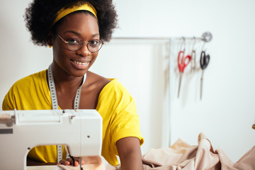 african woman seamstress sitting and sews on sewing machine. Hobby sewing as small business concept