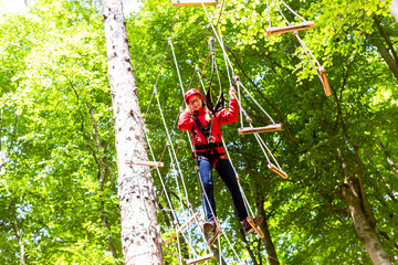 Child reaching platform climbing in high rope course in forest