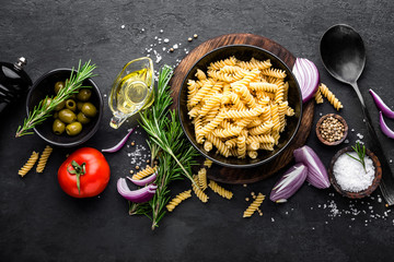 Wall Mural - Pasta and ingredients for cooking on black background, top view. Italian food