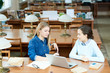 © Seventyfour - Attractive young friends having fun together while killing time before lecture in modern university library